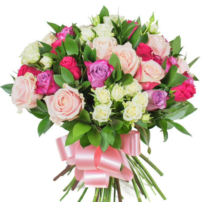 A lush, rounded bouquet presented on a clear white background, tightly hand-tied and bursting with mixed roses and rich greenery - the kind of arrangement we create at Flowers Tufnell Park for local celebrations. Large, classic roses in soft pastel pink and creamy white dominate the mass, some blossoms fully open to reveal layers of delicate, ribbed petals, others held in refined bud form for contrast and longevity. Punctuating this gentle base are striking magenta-fuchsia roses that introduce vivid accent notes, and a scattering of light lavender blooms that add cool, romantic depth to the colour story. Nestled throughout, clusters of petite spray roses - mostly creamy with subtle pale-yellow centers - create a lovely shift in scale and a tapestry-like texture between the larger heads. Abundant dark-green foliage, likely ruscus or salal, is artfully interwoven; the glossy, spear-shaped leaves provide a verdant backdrop that heightens the flowers' hues. At the stems' base, a thick bundle is tidily bound and dressed with a wide baby-pink satin ribbon tied into an elegant, voluminous bow, its lustrous surface catching the light and echoing the bouquet's soft, celebratory air. The overall effect is fresh and uplifting, with an implied scent of roses and green leaves that suggests a garden-picked intimacy. Perfect for birthdays, anniversaries, or a heartfelt 'thank you' delivered across Tufnell Park or to homes near Junction Road and Dartmouth Park, this bouquet embodies thoughtful craftsmanship and neighbourhood charm.