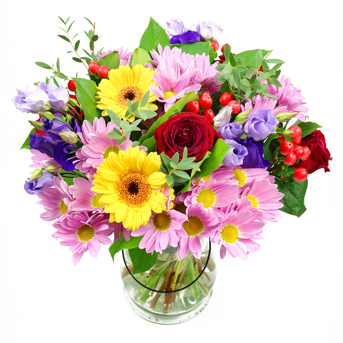 In this image, a substantial mixed bouquet rises proudly from a cylindrical clear glass vase, set before a bright white background that makes the colours almost glow. At its core, plush red roses with velvety, tightly layered petals introduce a sense of romance and timeless elegance, like a classic gesture exchanged between neighbours on Tufnell Park Road. Flanking them are two bold yellow gerbera daisies with dark, warm-toned centres, their large, open faces turning the composition towards joy and celebration, as if echoing the liveliness of local cafés and shops off Fortess Road. Encircling these central blooms, generous clusters of soft pink daisies or chrysanthemums spread outward, their many slim petals ruffling gently around sunny little centres, giving the bouquet a cushion of pastel softness and airy volume. Threaded throughout are stems of purple and lavender lisianthus, some still in bud and others open into graceful bell-shaped flowers, adding a cool, refined note and a silky texture that contrasts beautifully with the fluffier daisies. Scattered among the blooms are small clusters of bright red hypericum berries, round and glossy, which catch the light and introduce a playful texture and an echo of the roses' rich crimson tone. The arrangement is supported by a mix of lush green foliage, from broad, deep-green leaves to lighter, almost feathery sprigs, creating a frame of natural freshness reminiscent of nearby green spaces around Hampstead Heath and Dartmouth Park. Inside the glass vase, straight, well-prepared stems are clearly visible, immersed in clean water, suggesting careful conditioning by an experienced local florist. This bouquet radiates a spirit of generous happiness, ideal for lighting up a Tufnell Park home as a birthday surprise, a get-well wish, or a simple, heartfelt thinking of you.