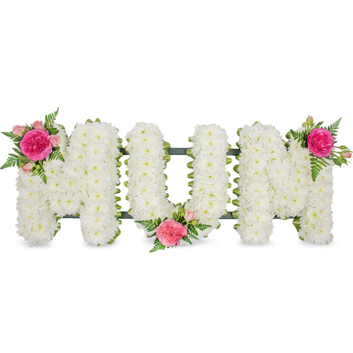 This image shows a beautifully balanced sympathy flower tribute spelling the word MUM in large, upright capital letters, evocative of the bespoke funeral flowers regularly arranged for families in Tufnell Park and along Fortess Road. Each letter is meticulously filled with countless white spray chrysanthemums, so tightly arranged that the blooms resemble a continuous, plush fabric of petals. The flowers are fresh and slightly domed, lending a gentle three-dimensional shape to the word, as though the letters are softly rising from the background. Their pure white tone symbolises innocence, remembrance, and a calm farewell, ideal for a loving final message from children or grandchildren. Beneath the flowers, a dark green supporting frame and ribbon edging can be glimpsed, outlining the bottoms and sides of the letters and providing the sturdy base that holds the tribute together when placed at a funeral service, crematorium chapel, or graveside. To prevent the white from feeling stark, the florist has introduced three identical sprays of colour. On the upper left corner of the first M sits a vivid fuchsia garden rose at full openness, accompanied by smaller dusky pink spray roses and light green fern fronds, the petals layered and velvety. A companion cluster nestles in the lower curve of the U, almost as if cupping the central letter, while a third spray crowns the upper right corner of the final M, creating a gentle visual rhythm from left to right. The balance of white chrysanthemums, pink roses, and airy greenery gives the piece a tender, feminine character, making it a fitting floral tribute for a beloved mother, perhaps travelling with the family from a Tufnell Park home to a nearby North London chapel.