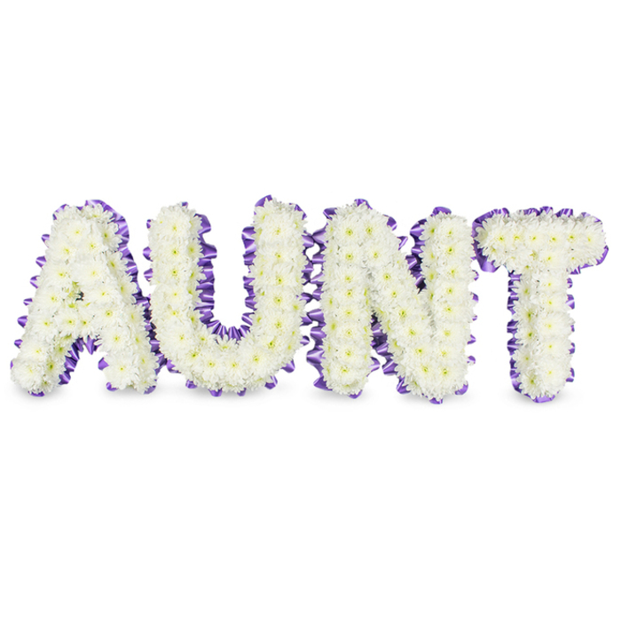 This personalised floral message presents the word AUNT in large, carefully formed letters, each letter a dense composition of small, immaculate white spray chrysanthemums. The surface of every character reads like a soft textile: hundreds of tiny petals layered to create a plush, cloudlike finish, with occasional pale yellow centres dimpling the white surface and lending natural depth and warmth. A luxurious deep purple satin ribbon is laid around the edges of each letter, worked into gentle ruffles and pleats that add sculptural detail and a refined boundary against the white blooms. Set on a pristine white field, the letters take on a serene presence; subtle grey shadows beneath them define the depth and hint at the metal or foam armature beneath, evidence of precise florist craftsmanship. The lilies' quiet green fragrance is absent here, replaced by the chrysanthemum's light, clean aroma-freshly conditioned and softly vegetal-evoking early-morning preparation in a small workshop. Emotionally the piece reads as both respectful and intimate: white for remembrance and purity, purple for dignity and affection. This style is often chosen for funeral services, memorial displays, or church tributes in and around Tufnell Park and nearby Kentish Town, where families seek a bespoke remit to honour a cherished aunt. The design balances formal structure and gentle comfort, offering a calm visual focus for mourning and memory.