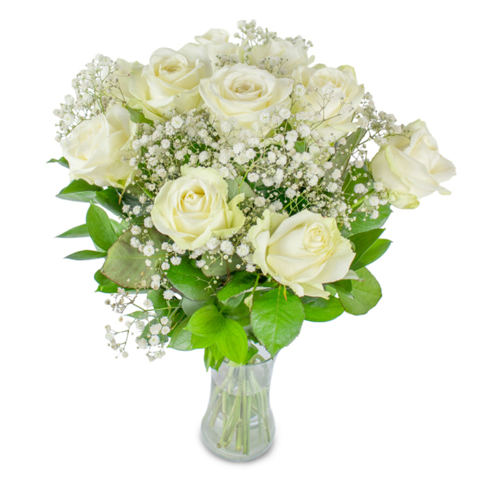 This composed bouquet of about a dozen creamy white roses and abundant baby's breath rests in a plain clear glass vase against a crisp white background, each element described with attentive care. The roses display a gentle variety of openness-some blooms are fully relaxed, petals layered and velvety, while others hold tighter, promising a slow, graceful unfurling; their soft ivory tones are lit by even, diffused light that emphasizes texture rather than bold colour. Interspersed throughout, the fine sprays of gypsophila lend a starlit, lace-like texture that lifts the heavier rose heads and creates an impression of lightness and air. Beneath and between, clusters of vivid green leaves-from deep, cool greens to brighter lime accents-frame the bouquet and provide a verdant counterpoint that heightens the whites' clarity.
The clear vase offers a candid view of trimmed stems and a visible water line, a small, honest detail that reassures about freshness and the careful trimming and conditioning each stem has received. In my experience as a florist serving Tufnell Park and the surrounding streets like Fortess Road and Holloway Road, clients select this style for wedding tables, commemorative events, or as a peaceful home gesture because it reads as both classic and quietly radiant. The scent is subtle, the visual language one of purity and composed affection-a gentle, meticulously balanced arrangement that invites reflection and calm.