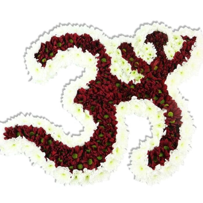A meticulously fashioned floral Om (Aum), presented against a clean white field so every curve and punctuation reads with clarity and devotion. The main mass of the symbol is formed from countless small, dark red to maroon chrysanthemum-style blooms, their compact heads packed so closely that the symbol's '3'-like upper curve, flowing downward stroke, and the crescent-and-dot motif emerge as a single, velvety surface. Tiny lime-green centers peek out from many of the red blossoms, giving the interior a quiet, jewel-like liveliness and subtle texture under soft lighting. Encircling and defining the icon is a broad, undulating rim of pure white spray chrysanthemums whose delicate petals create a crisp silhouette and accentuate interior negative spaces. The arrangement reads as sculptural work-dense, layered petals forming a soft relief-and a faint drop shadow beneath it indicates the piece's dimensionality and presence. Tactile impressions come to mind: the petals would feel cool and satiny, the layered surface cushioned, the whole bouquet an object of careful handling. The scent is mild and earthy, the kind of fragrance that recalls the flower stalls near Tufnell Park station on a quiet morning. Crafted with thoughtful technique appropriate for temple offerings, commemorative displays, or mindful gatherings, this piece is the sort of bespoke tribute local residents might commission for a funeral or cultural event in the Tufnell Park and Kentish Town area. For specially arranged pieces like this, Flowers Tufnell Park works with local families and event organisers to respect ritual and proportion.