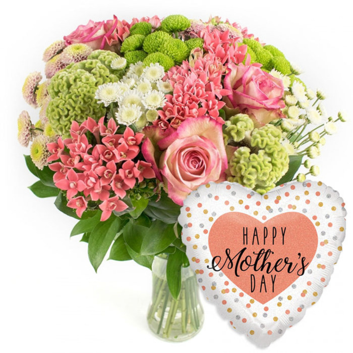 A lavish Mother's Day arrangement is captured in a bright, uncluttered product-style photograph, making every petal and reflection stand out as clearly as a window display on Junction Road near Tufnell Park. The composition is simple yet striking: on the left sits a domed bouquet in a clear glass vase, on the right a single heart-shaped foil balloon, both set against a plain white background. The bouquet itself is a harmonious blend of pink, coral, lime green, and white tones. Several stately pink roses provide a romantic focal point, their petals fading from deeper pink at the centre to softer, lighter edges that speak of tenderness and affection. Around them gather dense clusters of small coral-pink blooms, similar to kalanchoe or spiky spray flowers, adding a warm, celebratory glow. Lime-green button chrysanthemums and fluffy chartreuse, cockscomb-like elements give the design a modern, almost playful twist, their frilly surfaces adding movement and interest. Delicate white spray chrysanthemums and tiny daisy-style flowers are threaded throughout, catching the light and creating a sense of airiness. A halo of dark green foliage grounds the arrangement, offering both visual depth and a natural contrast that highlights the brighter blossoms. The transparent vase shows neatly cut stems and clear water, suggesting expert conditioning by a local florist to ensure freshness for same-day delivery around Tufnell Park. To the right, the heart-shaped foil balloon glints with a festive sheen. It has a white ground dotted with irregular gold, silver, and coral-pink spots, and at its centre a solid peach heart bearing the message HAPPY Mother's DAY in elegant black fonts. Together they form a thoughtful, ready-made Mother's Day gift, ideal for sending love to a mum in one of Tufnell Park's cosy terraced homes.