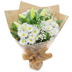 This bouquet celebrates the simplicity of white with a layered, tactile composition that feels both refined and approachable. Bright white chrysanthemum heads dominate the visual field, each petal neatly radiating from a soft yellow centre that lends the cluster an optimistic, sunlit quality even in subdued studio lighting. Vertical accents of pale green-yellow lily buds interrupt the rounded chrysanthemums; their closed forms add sculptural rhythm and the expectation of future bloom, while the lilies' faintly striped sheaths hint at a deeper colour to come. Scattered throughout, delicate sprays of gypsophila provide a gossamer veil, their tiny blossoms creating a soft, dreamy texture that lets the larger flowers breathe. Dark green foliage anchors the arrangement: glossy leaves and structured greenery bring depth, a cool contrast that intensifies the whites.

The artisan wrapping combines rustic and polished details-an inner sheet of natural, crumpled kraft paper for warmth, then a clear cellophane layer that shields petals and reads crisp against the white background. The gathered base is secured to create a tidy, portable presentation, practical for hand delivery or easy placing in a vase. The overall scent profile is subtle and clean, with a faint green, freshly-cut aroma and the lily's whisper of sweetness. As a seasoned florist might suggest to a customer in Tufnell Park looking for a thoughtful, versatile gift, this bouquet suits celebrations, quiet remembrances, get-well wishes, or simply to brighten a neighbour's day, especially when the morning light on Junction Road inspires gentle, understated gestures.