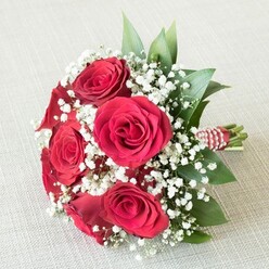 Capturing the essence of romance amidst Tufnell Park's leafy avenues, this exquisite bouquet brings together a lush assembly of velvet-textured red roses, each bloom opening gracefully to reveal a swirl of deep, crimson petals. Intermingled amongst these bold flowers, clusters of snowy white baby's breath evoke a gentle, dreamlike atmosphere, reminiscent of morning mists drifting over Tufnell Park's quiet gardens. Slender, vibrant green foliage-possibly freshly sourced salal or ruscus-peeks through, its natural sheen catching the light and adding depth to the design, echoing the park's abundant greenery. Gathering the bouquet, the stems are tightly bound with a charming red and white striped ribbon, finished with a twist of delicate pearl strands-an understated nod to the timeless traditions found at local weddings and celebrations. Resting upon a softly textured, cream-coloured fabric backdrop, the bouquet's rich hues and textures stand out, inviting tactile appreciation and imagination for its subtle floral fragrance. This arrangement is a celebration of love, joy, and artistry-ideal for marking significant moments like anniversaries, Valentine's Day, or for bridesmaids attending a wedding near Dartmouth Park Hill. Each element of the bouquet reflects the skilled hands and thoughtful touch of a local florist, promising freshness and a touch of Tufnell Park character to every special occasion.