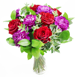 This luxurious bouquet in a clear glass vase showcases the kind of meticulous craftsmanship you might expect from a seasoned florist working right here in Tufnell Park. At its heart, richly coloured red roses unfurl in generous spirals, every bloom at that perfect moment between bud and full openness, their velvety petals creating a sense of warmth and passionate energy. Threaded between them, plump purple peonies add a softer, more rounded silhouette, their many ruffled petals catching the light in subtle shades of violet and plum, suggesting abundance and gentle romance. Surrounding the flowers, a thoughtful mix of glossy green foliage and slender eucalyptus stems adds texture and balance. The eucalyptus, with its muted silver-green leaves, arcs gracefully through the arrangement, giving a light, airy frame that stops the bold colours from feeling heavy, like a cool breeze moving through a summer garden behind a Tufnell Park terrace. The clear vase is understated and elegant, allowing the neatly trimmed stems to show through the water, emphasising the care and skill that shaped this design. Light seems to fall from one side, casting soft shadows and making the reds and purples appear almost luminous, as though the bouquet were glowing on a dining table near Tufnell Park station, ready for an evening celebration. One can imagine the delicate scent-a blend of sweet rose and fresh greenery-gently filling the room without overpowering it. Perfect for romantic gestures, congratulating a personal achievement, or brightening a home with same-day delivery across Tufnell Park and neighbouring streets, this arrangement communicates thoughtfulness, confidence, and genuine affection.