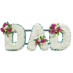 This image presents a bespoke funeral lettering piece spelling DAD, each letter lovingly composed from hundreds of small, snow-white chrysanthemums to form a plush, voluminous surface that reads as both soft and substantial. The letters are bordered by a vivid emerald-green pleated ribbon that crisply defines the contours and adds a restrained flourish of colour against the white blooms. Thoughtful clusters of deep fuchsia-magenta roses, some tightly furled and others gently opening, are arranged with small white freesia or similar spray flowers and dense dark-green foliage; one cluster accents the upper left of the first D, another nestles into the A's lower V, and the final cluster rests on the upper right curve of the last D. A low-profile dark green bar discreetly connects and supports the letters from behind, indicating the piece is made to stand at a funeral service, church entrance, or graveside. The scent suggestion is gentle - the faint honeyed rose notes meeting the fresh, citrusy lift of freesia and the clean, leafy green of foliage - while the visual effect is calm and respectful. As a Tufnell Park florist familiar with local needs around Junction Road and Dartmouth Park Hill, I imagine this tribute arriving for a small family service or placed near a memorial table in soft, overcast London light. Flowers Tufnell Park can craft similar bespoke lettering for local delivery across Tufnell Park and neighbouring Archway, ensuring the arrangement reads clearly from a distance while rewarding close attention with careful detailing.