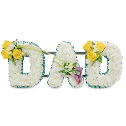 An elegant, personalised funeral tribute spelling out DAD in large, freestanding block letters, each letter handcrafted from a dense carpet of pristine white chrysanthemums that create a soft, pillowy surface. Every letter is framed by a ruffled dark green satin ribbon, the deep verdant edge giving definition and a touch of formality while complementing the fresh foliage interwoven through the design. Slim, dark green metal bars run horizontally behind the letters, visible at the rear, providing a sturdy structure that keeps the three pieces aligned as a single memorial statement. On the left D a bright cluster of sunlit yellow roses, around three to four blooms in full opening, is artfully placed on the upper curve, accompanied by tiny white freesias or gypsophila and leafy greens; two long, slender bare stems sweep diagonally from this cluster toward the A, adding a graceful line through the arrangement. The central A is softened with a refined bouquet on its lower diagonal, featuring two striking deep purple or burgundy calla lilies whose smooth, sculpted forms bring quiet dignity, set among small white fillers and glossy leaves. The right D mirrors the left, repeating the yellow rose cluster to close the visual loop. Soft, neutral studio lighting highlights the textures and the faint, clean scent of freesias and roses. Prepared with the care you would expect from a local Tufnell Park florist, Flowers Tufnell Park creates this piece to comfort families at funerals and memorial services across Fortess Road, Archway and surrounding neighbourhoods.