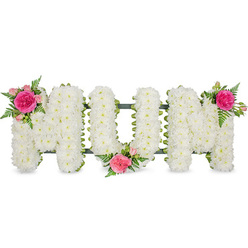 Centred against a clean white backdrop, a traditional funeral flower arrangement quietly spells out MUM in large, capital block letters, the kind of thoughtful tribute often seen at services around Tufnell Park, Dartmouth Park, and Archway. Every letter is densely covered in pristine white spray chrysanthemums, each tiny bloom pressed closely to the next so the surface appears like a soft, cushioned blanket of petals. There is a gentle, velvety texture to the flowers, suggesting both comfort and calm, while the uniform white colour conveys respect and a sense of stillness. Along the base of the letters a dark green framework and ribbon edging peeks through, hinting at the sturdy structure that supports the tribute as it rests on a stand or coffin spray bar. To break the expanse of white and to express a more personal emotion, three carefully placed clusters of brighter flowers have been tucked into the design. On the top left of the first M, a rich fuchsia garden rose unfolds in full bloom, ringed by smaller soft pink spray roses and airy fern foliage. A second cluster mirrors this at the lower middle of the U, nestling into the curve like a gentle embrace, and a third sits proudly on the upper right of the final M. These pink and fuchsia tones introduce warmth and affection, while the green fern adds a light, natural movement. The overall effect is of a deeply loving, custom-made tribute for a mother, something a local Tufnell Park florist might prepare for a family wishing to honour a lifetime of care and kindness.