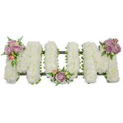 This thoughtfully arranged sympathy display spells out "MUM" in large, upright letters, each letter formed by a dense layer of bright white chrysanthemums or similar petite white flowers that create a plush, textured surface reminiscent of fresh snowfall. The pristine white plays softly in the light, evoking purity and peaceful remembrance. Accenting the letters are three small, artful groupings of roses in muted lavender and soft pink-one placed on the upper left arm of the first "M", a second nestled in the curved base of the central "U", and a third crowning the upper right arm of the final "M". The roses range from open blooms to tight buds, their velvet petals offering gentle perfume and a tender contrast in shape and hue. Interspersed among the flowers are sprays of vivid green foliage and slender fern fronds whose delicate fronds and lighter-green leaves add movement and depth across the piece. A darker structural frame, possibly ribbon-wrapped or moss-covered, is visible at the base and along the letter seams, providing support and a subtle outline beneath the white blooms so the letters retain their crisp form when displayed at a service. The composition radiates a quiet compassion-clean, restrained and intimate-suitable for a funeral, memorial or graveside tribute where the combination of white chrysanthemums and pastel roses conveys lasting love and respectful remembrance of a mother or maternal figure in a dignified, heartfelt manner.