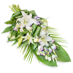 An elegant sympathy spray of white lilies and lisianthus is arranged in a long, graceful line, resting against a seamless white backdrop that lets every detail of the flowers speak clearly. The composition begins in a fuller, rounded cluster where the stems meet, then gently narrows to a soft, pointed tip, creating a teardrop shape often chosen for funeral and memorial services in and around Tufnell Park. Dominating the piece are several white oriental lilies, their large, trumpet-shaped blooms opening like quiet stars, each petal smooth and slightly curved with a faint sheen, while nearby buds remain slender and upright, suggesting life still unfolding. Threaded among them are stems of white lisianthus, some fully open with ruffled, cup-like petals delicately brushed with lavender tones along the edges, others closed tight in pale green buds that add rhythm and depth. The greens beneath are lush and carefully composed: broad, dark leaves form a strong, grounded base, while other leaves are rolled, folded, and twisted into sculptural forms that reveal the florist's skilled hand. Long, arching fronds extend from one side, their linear shape guiding the eye along the full length of the spray and adding a sense of movement, like a gentle breeze passing through a garden near Hampstead Heath on a still afternoon. Every element feels cool and fresh, from the waxy leaves to the soft, velvety petals, creating an atmosphere of calm respect. This floral sheaf would be a dignified tribute for a service, a wake, or a moment of private remembrance at home in Tufnell Park.