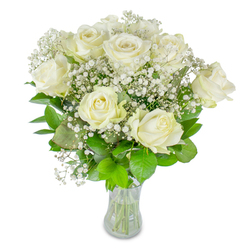 A classic, elegantly arranged bunch of roughly twelve pristine white roses is shown in a clear glass vase on a bright white backdrop, each rose revealing its own stage of bloom-from fully unfurled, satiny petals to the softer, sculpted curve of newly opening buds. These principal blooms are lovingly interwoven with abundant sprigs of baby's breath, their tiny pinhead flowers creating an airy halo that softens the bouquet's silhouette and gives the whole composition a dreamy, cloud-like texture. Rich green foliage, varying from deep emerald to a lighter, spring green, provides a grounded base and subtle movement, the leaves' glossy surfaces catching light and enhancing the contrast with the creamy whites.

Through the vase you can see the neatly cut stems and clear water, a small but confirming sign of freshness and careful florist technique. The image conveys quiet celebration and refined restraint-perfect for milestone moments such as weddings, anniversaries, or tender sympathy gestures. Locally, this is the sort of arrangement we prepare often for deliveries around Tufnell Park station and nearby Dartmouth Park, chosen for its serene presence and soft fragrance that fills a room without overpowering it. The overall impression is one of calm elegance and thoughtful composition, a bouquet that speaks in whispers of purity, love, and steady affection.