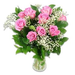 A thoughtfully arranged bouquet of pink roses and white baby's breath sits in a clear glass vase, poised against a pure white background where every petal and leaf is clearly visible. Around ten to twelve roses are gathered in a full, slightly domed shape, their petals curling outward in soft spirals that create a lush, almost cushion-like texture. The pinks range from gentle baby-blush tones on the outer petals to more medium rosy hues at the centre of some blooms, giving the eye subtle variations to explore. Threaded delicately among the roses, sprays of baby's breath reach out in fine, branching stems, bearing clusters of tiny white flowers that add a veil of softness and a feeling of light, airy movement through the bouquet. Rich green foliage circles the base of the blooms and peeks between them, offering a deep contrast that helps the pastel shades stand out. The stems, visible through the clear water in the vase, are evenly trimmed and slightly splayed, suggesting fresh preparation on the workbench of a Tufnell Park florist. Light falls evenly over the arrangement, producing soft highlights on the petals and gentle reflections on the glass while avoiding strong shadows, so the overall scene feels calm and spacious. There is a quiet joy in the bouquet's design-neither overstated nor minimal-that makes it especially suitable for baby celebrations, from a thoughtful delivery to new parents near Tufnell Park underground station, to a charming floral accent for a small family gathering in a local flat, or a welcoming touch in a newborn's room overlooking leafy North London streets.