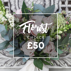 Caught in gentle, diffused daylight, this hand-tied bouquet reads like a small, private garden offered as a gift. Prominent soft blush roses form the heart of the arrangement, their layered petals soft to the touch and romantic in tone, while clusters of crisp white berries-resembling snowberries-punctuate the composition with bright, cheerful contrast. The eucalyptus leaves, in muted blue-green tones, create a cool, calming backdrop, their rounded shapes and faintly dusty surface balancing the roses' warmth and adding a subtle aromatic lift. Interlaced throughout are tiny white filler blooms that bring an ethereal, cloud-like lightness, and occasional deeper pink or burgundy sprigs that draw the eye inward and provide gentle shadow. Slender green-and-white flower spikes at the edges add movement and height, giving the bouquet a relaxed, garden-picked silhouette. The stems are neatly tied with a cream-coloured ribbon, and the whole rests against an ornate, pale carved stone or plaster background that suggests a classic interior in the Tufnell Park area. The tactile contrast between velvety petals and waxy foliage invites one to imagine running a hand over the arrangement, while the scent of eucalyptus and fresh cut roses offers quiet, soothing reassurance. Ideal for new-home welcomes around Junction Road, thoughtful thank-you gifts, or simply to mark a seasonal change, this bouquet embodies careful craftsmanship and local character for deliveries across Tufnell Park and neighbouring Dartmouth Park.