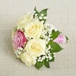 A compact and graceful bouquet, designed with local Tufnell Park flair, rests lightly on a canvas of pale, woven linen that echoes the area's blend of heritage and modernity. The striking central focus is a collection of creamy white roses, their petals unfurling in layers that suggest both softness and resilience. Offset in the cluster, a single magenta rose introduces a bold flash of colour-its vividness reminiscent of the pop-up floral displays along Brecknock Road in spring. Entwined among the larger blooms, clouds of pure white baby's breath impart a classic, airy feel, while glossy green foliage peeks out for balance and freshness. Each stem has been carefully bound in a bright pink ribbon, its silky sheen providing both visual delight and a nod to traditional bridal elegance. Spirals of delicate white pearls wrap the handle, lending gentle radiance and sophistication, especially as they catch diffused morning light. Every petal and leaf appears tended with care, the entire arrangement radiating joy and refinement-an ideal choice for Tufnell Park weddings, bridal parties or celebrations where subtle beauty and heartfelt artistry are cherished. This bouquet showcases floral craftsmanship tailored to the character of North London's most distinctive corners, delighting the senses and elevating special occasions.