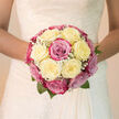 A hand-tied bridal bouquet glows softly, as if lit by the pale sunshine that falls across the Victorian terraces around Tufnell Park station. At its heart are creamy white roses, their petals luminous and plush, unfolding in perfectly layered whorls. Intertwined with them are blush-pink and soft magenta roses that appear gently kissed by morning light, the colours flowing from delicate pastel to deeper, romantic tones. Wisps of white baby's breath weave through the composition, adding a fine, lace-like texture that blurs the lines between each bloom, creating a dreamy, clouded effect. The bouquet is shaped into a graceful, symmetrical dome that would cradle beautifully against a lace or satin wedding dress, its proportions thoughtfully judged by the florist's practiced eye. The petals look almost cool and silk-like, inviting a tender touch, while the imagined fragrance is subtle yet captivating-a blend of classic rose perfume with the freshness you might associate with strolling past the trees and gardens off Campdale Road in early spring. The soft green foliage tucked just beneath the blooms offers a gentle contrast, suggesting life, renewal, and the quiet excitement of a day filled with new beginnings. Arranged to echo the purity and optimism of a wedding day in Tufnell Park, this bouquet feels as intimate as a whispered vow, bringing together elegance, emotion, and the timeless romance that so many North London couples cherish in their wedding flowers.