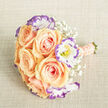Captured from a slightly raised angle on a neutral, light beige linen-like cloth, this hand-tied bouquet centres on creamy apricot-peach roses whose layered petals open like warm, delicate shells. Ruffled white lisianthus are threaded between the roses, their edges kissed with a vivid violet-purple that creates a lively, contemporary contrast while revealing soft yellow stamens at the centre of each bloom. Scattered gently throughout are clouds of baby's breath (Gypsophila), whose tiny white flowers produce an airy, dreamlike veil that lightens the arrangement and enhances depth. The stems are bound with a blush-peach ribbon, wrapped smoothly and studded with several rows of small, pearly beads that lend a tactile sense of luxury; the neatly trimmed green stems peek from the end, grounding the bouquet in natural freshness. Soft, even light washes over the composition, accentuating the satin sheen on petals and the subtle interplay of warm and cool tones. As a local florist I picture this bouquet arriving for a Tufnell Park wedding or a thoughtful celebration after a stroll past Tufnell Park tube and Fortess Road; the scent is quietly floral, reminiscent of early morning blooms. Prepared with care by Flowers Tufnell Park, it suits bridal parties, delicate table centres, or an intimate present for anniversaries and new beginnings across Dartmouth Park and nearby streets. The overall effect is refined, romantic and quietly elegant - a composition that feels handcrafted and neighbourhood-ready.