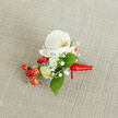 A delicately styled boutonniere lies on a softly textured, light beige linen-like fabric, its woven threads creating a warm, natural backdrop that feels right at home in a Tufnell Park townhouse near Fortess Road. At the heart of the design is a pristine white Phalaenopsis orchid, its broad, velvety petals unfurling with calm elegance. The orchid's centre holds a whisper of creamy yellow and soft orange in the throat, adding gentle warmth and depth to the bloom. Encircling it, tiny white clouds of baby's breath float in airy clusters, each miniature floret catching the light and adding a gossamer softness that contrasts with the orchid's smooth surface. Tucked among the flowers, glossy, round red berries glow with a rich, festive intensity, their polished skins suggesting winter celebrations and evening gatherings along Tufnell Park Road. A few paler green, oval buds nestle beside them, hinting at freshness and new beginnings. Slender and broader green leaves in varying shades are carefully threaded through the piece, their clean lines framing the central flower and tying together the red and white tones. At the base, a vivid red satin ribbon is wrapped neatly and tied in a small, precise knot, its short tails resting gently against the fabric as though ready to be pinned to a groom's lapel or worn as a petite corsage. The overall composition feels refined yet inviting, the kind of handcrafted floral detail chosen for weddings, proms, or intimate celebrations across Tufnell Park, capturing a sense of thoughtful preparation and quiet joy.