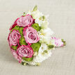 Set against a softly woven, light beige backdrop that looks like natural linen laid out on a calm Tufnell Park morning, this hand-tied bouquet lies gracefully on its side, inviting the eye to wander from left to right. At its centre, generous pink roses open in plush spirals, their petals graduating from a delicate powder blush in the middle to a richer magenta flush along the ruffled outer edges, like the sky shifting at dusk over nearby Hampstead Heath. Tucked between these romantic blooms are rounded clusters of lime green button chrysanthemums, the tiny, tightly packed florets forming cheerful, bumpy spheres that add both structure and a fresh, almost citrus brightness to the palette. Towards the right, a halo of white lisianthus softens the composition, their petals gently frilled, some flowers fully blooming in shades of creamy white, others still in elegant buds that promise to unfold. The stems are gathered with attentive care, wrapped smoothly in a blush satin ribbon that feels silky to the touch, then adorned with multiple strands of luminous white pearls winding neatly around the handle, giving a nod to timeless bridal elegance. Resting on the neutral fabric, the bouquet's vivid pinks, greens, and whites stand out clearly, yet harmoniously, evoking a sense of poised celebration. It feels like a bouquet created for a bride stepping out from a townhouse near Tufnell Park or Archway, or for a special delivery marking an engagement, anniversary, or intimate celebration in one of the quiet streets just off Holloway Road.