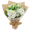 A hand-tied bouquet of pristine white blooms stands upright against a clean white backdrop, its composition quietly confident and soothing. At the heart, clusters of daisy-like white chrysanthemums fan countless narrow petals around sunny yellow centres, their crisp faces catching a soft, cool light that emphasizes the flowers' fresh, papery texture. Among them, elongated pale green-yellow lily buds rise like gentle promises, some with faint striping on their outer petals; they are closed in the photograph but suggest an unfolding sweetness and a graceful change to come. Wisps of baby's breath (Gypsophila) drift through the arrangement, their tiny white clouds providing feather-light contrast and a delicate halo around the larger heads. Deep green foliage-broad, glossy leaves and slimmer stems-frames the bouquet, giving weight and a verdant counterpoint to the bright whites.
The stems are gathered with a practiced hand and wrapped in a layer of crinkled brown kraft paper that lends an organic, rustic warmth, while a clear cellophane outer sheet protects the blooms and adds a subtle gleam. The base is neatly gathered and tied, forming a small standing pocket so the bouquet can be displayed or carried easily. There is a cool, clean scent: a faint green-leaf freshness with the soft vegetal sweetness of lilies waiting to open. This arrangement reads as both celebratory and contemplative-equally apt for birthdays or new beginnings, a gentle thank-you, or as a calm expression of sympathy-and feels like something a local Tufnell Park florist might hand over on a quiet morning near Fortess Road or Dartmouth Park Road.