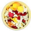 From a bird's-eye view, the photograph focuses entirely on a round, pale cream ceramic bowl so filled with petals that the rim seems to cradle a little lake of colour. Large rose petals dominate the surface, their shapes full and slightly curled, showing velvety textures in rich crimson, vivid sunshine yellow, and soft peachy orange reminiscent of late summer light. Tucked throughout this warm spectrum are clusters of small, frilled white florets, likely hydrangea, their delicate paper-thin petals sitting lightly atop the heavier rose petals and creating a cool, soft contrast. The lighting is bright yet gentle, with no harsh shadows-just a clear, even illumination that makes the petals look freshly scattered, as if they have just been collected from arrangements made earlier in the day. The effect is lush and soothing, resembling a petal pool one might find readied in a quiet room before a funeral service in Tufnell Park or a memorial gathering near Gospel Oak. There is an almost tactile invitation in the way the petals lie-some folded upon themselves, others open and flat-suggesting that if you reached in, your hand would sink into layers of softness and release a faint, comforting cloud of rose fragrance. This simple bowl of petals seems ideal for gentle farewell rituals: adding colour to a graveside, marking the path to a chapel door, or offering mourners a symbolic handful to scatter in honour of someone dearly missed. The composition carries a deep sense of care and reverence, translating emotion into colour and touch.