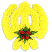 A carefully shaped floral Khanda sits against a pure white backdrop, its form sculpted from thousands of small, tightly clustered bright yellow chrysanthemum blooms that give the emblem a plush, slightly three-dimensional texture. The round chakkar (quoit) and the sweeping curves of the kirpans are traced in unbroken bands of sunny yellow petals, each tiny flower layered to follow the symbol's graceful lines so the whole piece reads cleanly from a distance yet reveals delicate petal detail close-up. At the very heart, where the chakram meets the central khanda, a compact cluster of deep red roses - five roses gathered closely - introduces a quiet focal point, their velvety petals and darker tones popping against the luminous yellow. Those roses are cradled in rich, dark green fern fronds that fan around the centre, their fine, feathery texture contrasting with the chrysanthemums' rounded heads and adding depth and a cool verdant note. Soft studio light from above catches the edges of the petals and casts a subtle grey shadow under the base, suggesting the weight and presence of a free-standing tribute appropriate for a remembrance service or religious ceremony. The scent is restrained: a faint, fresh chrysanthemum sweetness layered with the low, warm perfume of red rose and a green, slightly herbal hint from the ferns. As a florist working in and around Tufnell Park, I picture this piece standing respectfully in a gurdwara hall or placed at a memorial near Junction Road - a visual offering that balances vivid colour with solemn dignity for Sikh heritage events and remembrance occasions.