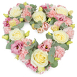 A lush heart-shaped wreath of pastel flowers is shown against a clean white background, its surface so densely packed with blooms that almost no gaps of greenery are visible. Creamy ivory and soft yellow roses form the backbone of the design, their full, layered petals opening in generous spirals that bring a classic, timeless feel. Around and between them, light pink carnations cluster in ruffled cushions, their softly frayed edges adding a gentle, comforting texture that suggests tenderness and care. Richer magenta-pink lisianthus blooms add depth and contrast, some with darker centres that pull the gaze deeper into the arrangement, like small windows of quiet reflection. Sprigs of silvery eucalyptus thread through the design, their cool, rounded leaves resting lightly on top of the petals and framing the heart's outline with a calm, muted green. Tiny yellow-green buds are scattered here and there, offering hints of new growth and reinforcing the sense of freshness you would expect from flowers prepared that morning in a Tufnell Park florist's studio. The overall mood is serene and compassionate, ideal for expressing sympathy, remembrance, and lasting affection. This heart-shaped tribute would sit beautifully beside a photograph at a memorial gathering, placed perhaps after a service in one of the nearby churches or funeral homes that serve the Tufnell Park community. Its pastel palette and soft textures make it especially suited to honouring a gentle personality, offering comfort to family and friends during moments of grief and reflection.