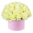 A beautifully composed hat box of roses dominates the scene, offering a sense of quiet opulence that feels perfectly suited to a Tufnell Park townhouse or a stylish apartment off Junction Road. The flowers are arranged in a lush, rounded dome, built from dozens of roses in gentle cream and pale ivory tones, with soft glimmers of pastel yellow glinting from their centres like captured morning light. Each rose is perfectly formed, its velvety petals layered in tidy spirals that curve outward, some blooms fully open and others just beginning to relax into their full shape. The roses are packed close enough that their petals nearly touch, giving the impression of a continuous, cloud-like surface. At the base of the blooms, discreet hints of fresh green foliage are just visible, offering a natural counterpoint to the pale petals without drawing attention away from them. The entire arrangement is cradled in a round pastel pink hat box, whose smooth, matte exterior suggests a high-quality, gift-ready finish-subtle, modern, and undeniably romantic. This soft blush base enhances the gentle tones of the roses while grounding the design in a contemporary gift aesthetic that many Tufnell Park couples favour for anniversaries and meaningful milestones. The background is bright white and free from any clutter, so the eye rests entirely on the interplay of colour, form, and texture. Together, the elements create a mood of tenderness and celebration, evoking the feeling of a thoughtfully chosen floral surprise delivered to a home near Tufnell Park station, where it might sit proudly on a coffee table or bedside cabinet, quietly marking a shared love story.