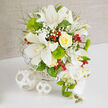 On a clean white tabletop, a lavish bridal-style bouquet is presented against a soft beige background, the overall effect as calm and composed as a quiet side street off Tufnell Park Road. Dominated by crisp whites and rich, layered greens, the arrangement glows with subtle highlights of buttery yellow and jewel-like red. At the centre, several white Oriental lilies open in full, their broad, satin petals gently curving back to reveal speckled throats and prominent stamens, as if caught in perfect bloom for a wedding morning. Close by, a tightly swirled yellow rose, with creamy petals arranged in flawless spirals, adds a warm focal point that feels both romantic and reassuring. Throughout the bouquet, airy clusters of white baby's breath form a delicate haze, softening edges and lending the look a dreamy, cloud-like texture. Almost spherical heads of bright Green Trick dianthus create a mossy, tactile contrast, their vivid green echoing the nearby green spaces of Dartmouth Park and Parliament Hill. Fine, feathery foliage and slender stems layer in between, giving the piece a natural, garden-inspired rhythm. Glossy red hypericum berries pop here and there, like tiny drops of garnet that bring in a sense of festive cheer, perfect for winter weddings or celebratory gatherings. Flowing gracefully down the right side, a cascade of pristine white Phalaenopsis orchids tumbles from the main body of the bouquet, each bloom smooth and luminous, some with soft yellow centres and accompanied by plump green buds and spiky accents that add structure. The whole design is anchored in a low, white woven basket, echoed by two matching wicker spheres resting on the table, making this arrangement ideal as a sophisticated centrepiece for a Tufnell Park reception or registry office celebration, beautifully styled by local florists.