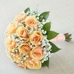 A vision of romance and refinement crafted for the Tufnell Park community, this classic peach and apricot rose bouquet radiates both tenderness and grace. Each rose unfurls its petals in lyrical spirals-from the palest peach toward the heart's deeper apricot-in an arrangement that recalls intimate gatherings or wedding mornings near Campdale Road or the local markets. Interlaced with these luminous blooms, airy clouds of snowy white gypsophila bring a sense of weightless delight, much like the gentle breeze floating through Tufnell Park's open spaces. Glossy dark green leaves frame the bouquet, anchoring its warmth in nature's freshness and adding dimension to the gentle palette. The hand-tied stems, gathered with care, are finished with a soft peach satin ribbon adorned with a neat grid of satin-like faux pearls, promising both visual elegance and a gentle, inviting touch. Laid on a subtly textured neutral-hued linen, the bouquet harmonises with its surroundings, the soft natural light enhancing each hue and texture. It evokes a mood of hope and loving anticipation-the perfect accent for a Tufnell Park wedding, anniversary, or meaningful occasion where heartfelt celebration and skilled local artistry matter.