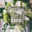 From a sunlit corner in north London, this Florist Choice bouquet by Flowers Tufnell Park exudes quiet luxury. Large white lilies dominate the arrangement, their petals unfurling with a pure, celestial grace, while clusters of bright lime-green elements-greens like Green Trick dianthus or compact hydrangea-pulse through the bouquet with modern energy. Surrounding them, soft white blooms, likely ranunculus or spray roses, add volume and texture, their petals velvety and luminous. A generous bed of dark green foliage, including eucalyptus leaves, threads through the composition, giving depth and a lush, natural base. The bouquet appears hand-tied, held by someone in a pale dress, with the blurred background hinting at a wedding or special occasion near Primrose Hill and Holloway Road. Center stage is a clean, white frame overlay bearing the words Florist Choice Bouquet in an elegant script, followed by a bold, uppercase BOUQUET and a prominent ?200 price, signaling premium status. The overall impression is one of refined sophistication-a contemporary floral statement that pairs timeless white with a fresh lime accent. Crafted for moments of celebration, it would brighten a wedding morning in Tufnell Park, as well as anniversaries and thoughtful gifts across Kentish Town and Archway, with the freshness and artistry you expect from Flowers Tufnell Park.