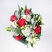 A lush hand-tied bouquet captured in soft daylight, filled with velvety red roses, ruffled pink-red carnations, and cloudlike white daisies and chrysanthemums, all cradled in fresh greenery. The roses sit at the heart of the arrangement, their deep crimson petals spiralling open like quiet promises, while the carnations surround them with feathery, almost velvet folds that add movement and texture. Clusters of tiny white chrysanthemums and sprigs of gypsophila float between the bolder blooms, giving the whole design a light, airy feel, as if a dusting of snow had settled delicately over the bouquet. Eucalyptus leaves curl elegantly at the edges, their muted blue-green tones and soft, herbal scent creating a cool balance against the warmth of the reds and pinks. Glossy tropical foliage and crisp garden-style leaves frame the flowers, giving structure without feeling stiff, the stems gathered neatly as if ready for same-day delivery to a townhouse or café table in Tufnell Park. The composition feels joyful yet composed, like a bright morning on Fortess Road when the shops first open and the streets are still calm. It's easy to imagine this bouquet resting on a windowsill overlooking Tufnell Park Road, catching patches of London light as the day moves on. Designed for birthdays, reunions, and heartfelt congratulations, the arrangement radiates optimism and affection, a burst of fresh colour and soft fragrance that instantly lifts the mood of any North London home or office it enters.