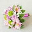 Photographed on a subtly textured beige fabric akin to the cozy textiles found in Tufnell Park homes, this vibrant bouquet is a triumph of local floristry, lovingly hand-tied by artisans well-versed in the tastes of Dartmouth Park and beyond. At its core are several soft pink roses, their multi-layered petals gently opening to reveal spiral centers-each blossom exudes delicate grace and hints at gentle romantic moments cherished in intimate gatherings along Stroud Green. Vibrant lime green button chrysanthemums, round and textured, dot the ensemble with playful energy, while pink alstroemeria bring an elegant, exotic flourish, their slender petals painted with soft yellow hues and intricate mahogany spots. Wisps of pure white baby's breath fill the arrangement with airy, feathery charm reminiscent of morning mists in Waterlow Park. Dark green leaves cradle the flowers, lending a lush richness that deepens the bouquet's palette. The hand-tied stems are wrapped in a vivid fuchsia satin ribbon, the bold colour providing a final flourish rarely missed in Tufnell Park's lively celebrations. Bathed in soft, even light, every detail-from texture to tone-shines. This bouquet, perfect for bridesmaids, anniversaries, or a spontaneous act of kindness, captures the warmth, artistry, and spirit of Tufnell Park, and can be delivered same day to neighbours along Brecknock Road and beyond.