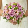 This radiant bridal bouquet, gathered with care in Tufnell Park, invites a sense of fresh romance and artistic flair. Blushing lavender roses in varying stages of bloom spiral gracefully beside delicate alstroemeria, whose pink petals are brushed with maroon and gold-a gentle nod to the area's artistic soul. Crisp lime green button chrysanthemums add a vibrant, modern spark, their textured globes infusing the bouquet with joyful energy akin to the green spaces at Tufnell Park. Threads of white baby's breath weave through the composition like morning mist across the northern skyline, softening edges and enhancing the overall serenity. Deep green leaves, full of life, provide a subtle, grounding presence, while the lace of the bride's gown frames the whole scene with understated luxury. Each flower is carefully placed to evoke the serenity and optimism that defines so many ceremonies held across the neighbourhood. The bouquet radiates warmth and hope-much like a sunlit stroll along local streets-serving as a heartfelt statement for intimate celebrations or anyone seeking elegant wedding inspiration rooted in local character.