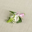 A delicately handcrafted boutonniere rests on a softly textured, light beige fabric background that looks like fine linen, the neutral surface allowing every petal and leaf to stand out clearly. At the heart of the piece is a single white alstroemeria bloom, its broad, slightly ruffled petals opening gently to reveal subtle reddish-brown speckles near the throat and pale green veins that catch the light. To the left, a tight lime-green spike of unopened buds, reminiscent of Ornithogalum, adds an architectural line and a fresh, almost springlike vibrancy. Threaded throughout are tiny clouds of white baby's breath, each minuscule flower forming a lacy halo around the focal bloom and softening the edges of the design. Supporting the flowers is a careful collar of foliage: dark green, sword-shaped leaves form a sturdy base, while finer, grass-like strands arc gracefully outward, introducing movement and airy texture. At the right side, the stems are gathered neatly and finished with a glossy pastel pink satin ribbon, tied into a small, precise bow that brings a romantic pop of colour without overpowering the quiet palette of white and green. The lighting is even and gentle, as if filtered through a calm afternoon window in a Tufnell Park townhouse, revealing each texture from the smooth satin to the velvety petals. The overall mood is refined and tender, like a buttonhole prepared for a wedding at a nearby North London registry office, ready to be pinned to a lapel for a ceremony, prom, or intimate celebration along the leafy streets between Tufnell Park Road and Fortess Road.