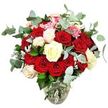 A richly romantic rose arrangement stands in a clear glass vase, photographed against a bright white background that makes every bloom appear vivid and defined. The bouquet is lush and generous, with around two dozen or more roses in tones of deep red and lively scarlet, some just beginning to open, others already unfurled into soft, velvety cups of overlapping petals that speak of passion and heartfelt emotion. Woven through this sea of red are creamy white and ivory roses, along with white flowers brushed at their edges with a hint of pale pink, adding softness and a sense of gentle light within the design. Tiny clusters of bright pink filler flowers, similar to mini carnations or delicate berries, break up the larger shapes and contribute a playful sparkle of colour and texture. Blue-green eucalyptus foliage, its rounded leaves smooth and slightly hazy in tone, drifts in and out between the roses, providing cool contrast and a modern, natural feel that suggests a clean, refreshing scent. Deeper green leaves and a touch of silvery-green foliage spread outward to create a full, domed outline, giving the impression of a carefully balanced but abundantly filled bouquet. The transparent vase, with its rounded base and narrowing neck, shows off the straight stems and clear water, subtly confirming the flowers' freshness and care. Seen as a whole, this arrangement feels like a classic romantic gift ready to appear in a Tufnell Park home near the quiet streets off Lady Somerset Road, perfect for an anniversary surprise, a declaration of love, or a grand thank-you that turns an ordinary day into something memorable.