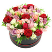 A lavish round hat box of roses sits centre stage against a pure white backdrop, photographed in a way that makes every petal and leaf feel almost touchable. The container is a sleek black cylinder, finished with a slim red trim at the base that echoes the deeper rose tones above it, creating a polished, designer look that would feel at home in a townhouse near Tufnell Park station. From this base, a generous dome of roses rises and gently spills outward, tightly packed so the blossoms form a continuous, quilt-like surface of colour. Rich red roses provide anchor points throughout the design, their velvety petals swirling inward like tiny whirlpools. Between them, blush pink and soft cream roses lend lightness, while warmer peach and coral blooms glow softly, recalling the warm hues of a summer sunset over Tufnell Park Fields. Splashes of bright fuchsia add excitement, and clusters of lavender or mauve roses introduce a calm, refined note that balances the overall palette. The arrangement is composed of both large, fully opened roses and smaller spray roses, whose dainty buds and partially opened heads add a sense of movement and unfolding life. Interwoven among the blooms, small, bright green leaves and touches of foliage break up the colour blocks, their crisp texture and refreshing tone making the roses appear even more vibrant. The lighting is even and gentle, casting minimal shadows so the focus remains on the interplay of colours, shapes, and layers. This hat box bouquet feels celebratory yet intimate, the kind of handcrafted floral design a local Tufnell Park florist might recommend for anniversaries, romantic gestures, or meaningful birthdays, bringing warmth and elegance into any North London home.