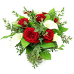 A sophisticated bouquet of red roses and white calla lilies is displayed in a clear glass vase, photographed against a stark white background that makes every colour and contour feel vivid and immediate, as if ready for delivery to a townhouse near Tufnell Park station. At the centre of the arrangement, several rich red roses open generously, their tightly layered petals forming velvety spirals that speak of romance and devotion. Their crimson hue is deep and saturated, catching the light just enough to show subtle variations from shadowed centre to glowing outer edges. Threaded between these classic blooms, white calla lilies stand and curve with quiet grace, each flower a pure, smooth funnel of creamy white wrapped around a slender yellow spadix. The lilies introduce a contemporary, almost sculptural element to the design, contrasting beautifully with the more traditional, ruffled form of the roses. Around the focal flowers, an ample selection of greenery brings texture and movement: graceful sprigs of eucalyptus with soft, rounded silvery-green leaves drift lightly over the edges, while robust, darker green leaves form a lush, structured base that supports the bouquet. Through the sides of the cylindrical glass vase, the viewer can see the neatly cut stems held together in clear water, underscoring the arrangement's freshness and careful preparation. The bright, even lighting reveals every detail-from the fine veins on the leaves to the satiny surfaces of the lily petals-creating a harmonious composition that feels ideal for anniversaries, romantic gestures, or elegant table centres in homes and venues throughout Tufnell Park.