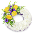 A deeply reverent circular funeral wreath carefully shaped like an 'O', photographed against a clean white backdrop to emphasize its simple dignity. The main ring is composed of hundreds of small, pristine white spray chrysanthemums, packed so closely their layered petals read as a plush, cloud-like band-soft to the eye, matte in texture, and quietly luminous in cool daylight. From the upper left curve springs the arrangement's single accent: several fully opened, warm golden-yellow roses whose petals spiral outward in buttery tones, paired with clusters of deep, royal purple Eustoma (lisianthus) whose ruffled, cup-shaped blooms lend a velvety counterpoint. A few pale lavender-and-green Eustoma buds peek through, promising gentle movement and depth. Interwoven among these flowers are fresh green leaves-glossy rounded foliage, subtle variegation on a few blades and delicate fern fronds-that give the spray structure, cool contrast and an organic, living edge. Along the inner and outer edges of the white chrysanthemum ring a fine dark purple mesh or crinoline ribbon peeks out, echoing the lisianthus tones and framing the wreath without overwhelming its serenity. The open center allows the eye to rest, creating a traditional shape meant for sympathy and memorial use, while the combination of white purity with yellow warmth and purple reverence conveys comfort and remembrance. Imagine this piece delivered to a quiet service in Tufnell Park or laid near a programme at a nearby chapel in Archway; its subtle scent of roses and the tactile softness of the chrysanthemums read as a careful, hand-crafted farewell for family and friends.
