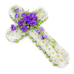 A serene funeral floral cross is displayed against a clean white backdrop, photographed from slightly above so the whole design feels clear, balanced, and contemplative. The cross is entirely encrusted with compact white chrysanthemums, tightly packed until they form a dense, cushion-like layer of petals. These blooms are crisp and fresh, each with a pale-green centre that adds gentle variation and a soft glow, reminiscent of morning light falling over Tufnell Park's terraced streets. Along the sides of the cross, a slim lime-green ribbon runs neatly from top to bottom, framing the arrangement and lending a bright, contemporary edge to the traditional Christian shape. At the point where the arms meet, a prominent cluster of rich purple lisianthus takes centre stage. Their ruffled, velvety petals open in layers, revealing deep tones of royal purple that stand in striking contrast to the pure white beneath, symbolising dignity, reverence, and heartfelt sorrow. Fine sprigs of variegated greenery and dainty filler flowers weave through the purple blooms, softening their edges and adding natural texture, as if freshly gathered from a nearby park or garden. From this central gathering, more lisianthus flowers and buds trail gracefully down the lower arm of the cross, forming a gentle diagonal cascade that adds elegance and movement. A soft natural shadow beneath the arrangement gives it a subtle three-dimensional quality, making it appear as though it rests lightly on a chapel table or memorial plinth. This carefully composed floral cross serves as a meaningful expression of sympathy and faith, suitable for funerals, wakes, or cemetery tributes for families in and around Tufnell Park.