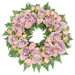 Laid flat on a spotless white background, this circular sympathy wreath forms a complete, graceful ring of roses and greenery, reminiscent of a carefully arranged tribute at a Tufnell Park chapel or along the quiet corners near Hampstead Heath. The design is rich and full, composed primarily of roses in a palette that whispers rather than shouts: large blooms in dusty lavender, antique mauve, and soft grey-purple, their petals opened wide to reveal layered, velvety spirals. These focal roses are evenly spaced around the circle, ensuring a sense of calm balance and visual harmony, while their cool, muted tones set a reflective, contemplative mood.
Threaded between them are clusters of smaller, pastel pink spray roses, some half-open, others held in tight buds, lending gentle movement and a touch of youthful softness. Each mini bloom acts like a small note of comfort in a larger symphony of remembrance. Underpinning the entire arrangement is a dense, verdant foundation of dark green ferns, likely leatherleaf or sword fern, whose feathery fronds radiate outwards, creating a rich, textural frame. The foliage peeks between the flowers, its deep green providing a striking yet natural contrast to the pastel petals. Tiny, darker filler greens and discreet buds nestle among the roses, adding depth and subtle shadows that make the wreath feel three-dimensional and tactile, as if you could almost brush your fingertips across the cool leaves and silky petals. The overall effect is one of serene dignity and heartfelt condolence, an ideal floral wreath for a funeral, memorial, or graveside tribute in and around Tufnell Park, expressing peace, respect, and an unbroken circle of memory.