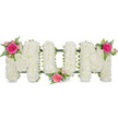 A carefully crafted funeral flower arrangement spells out the word MUM in striking yet gentle fashion, reminiscent of the personalised tributes often prepared by Tufnell Park florists for services across North London. Set against a bright, uncluttered white background, the three capital letters stand side by side, each shaped from a sturdy frame then entirely hidden beneath a dense covering of white spray chrysanthemums. These small, rounded blooms are packed so closely together that they create a soft, cushion-like texture, the petals forming a smooth, undulating surface that catches the light and gives a sense of quiet softness. The white chrysanthemums provide a calm, respectful base, suggesting purity and enduring love. Discreet bands of dark green framework and ribbon can be seen along the bottom of each letter, outlining the structure and gently anchoring the design. To bring warmth and individuality, three matching clusters of brighter flowers and foliage are woven into the lettering. On the top left of the first M, a vivid fuchsia garden rose unfolds among smaller, pale pink spray roses and delicate green fern leaves, introducing a romantic, feminine note. A second cluster sits at the lower centre of the U, almost cradling the middle of the word, and a final grouping nestles on the top right of the last M, completing the visual journey from left to right. The contrast of crisp white petals, rich pink roses, and fresh greenery creates a heartfelt, elegant tribute, suitable for honouring a much-loved mother at a funeral, memorial, or graveside gathering in and around Tufnell Park.