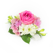 A compact, hand-crafted corsage sits against a pristine white background, composed with the assured touch of a neighbourhood florist in Tufnell Park. At its centre a lush bubblegum-fuchsia rose commands attention, young petals unfurling in tight concentric layers with a velvet softness that suggests a gentle, familiar scent. Encircling the rose, clusters of pale pink and lavender hydrangea florets create a cloud-like cushion, their papery petals adding volume and a romantic, springtime whisper. Interspersed are small, creamy white trumpet-shaped blooms-suggestive of miniature amaryllis or lilies-with subtle green throats that lend a cool, fresh contrast to the warm pinks. Deep, glossy emerald leaves tuck under the blooms, broad and supportive, their surfaces catching soft, natural light so the greens read as a lush foundation. Slim, vibrant green buds with soft yellow hints rise slightly from the sides, introducing a sense of upward movement and the promise of later opening. At the bottom right, a delicate cluster of luminous white pearls, varying gently in size, spills like an heirloom brooch and adds a satin shimmer against the floral textures. The overall impression is intimate and refined-ideal for a bride's wrist, a prom corsage, or an anniversary keepsake-evoking quiet confidence and fresh garden mornings near Tufnell Park tube and the leafy walks toward Dartmouth Park. The piece feels hand-touched, cool to the fingertips, lightly scented, and edited down to nothing but romance and clarity, described here with the care of an experienced local florist familiar with the light and gatherings of this corner of north London.