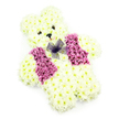 A tender teddy bear crafted from flowers sits alone against a bright white background, radiating softness and innocence that would feel at home in a peaceful Tufnell Park chapel or family front room. The bear's plump form is completely covered in crisp white and soft cream chrysanthemums, each bloom nestled closely to the next so that the surface appears like a finely stitched teddy rather than individual flowers. Its head is round and inviting, with little ears gently raised, while the arms and legs are shaped to look sturdy yet cuddly, as though ready for a child's embrace. Two tiny dark eyes and a small black nose create a gentle, almost listening expression, suggesting quiet companionship for those in mourning. Across the bear's chest, a waistcoat of vibrant deep pink and magenta flowers adds a cheerful splash of colour, the petals forming two curved panels that draw the eye to the centre. There, a dainty bow of sheer purple netting is tied neatly at the neckline, its translucent layers catching the light and adding a sense of ceremony, much like dressing a favourite toy for a special day. The flowers look freshly arranged, the heads full and bright, suggesting the skilled hands of a local florist accustomed to creating tributes for services around Tufnell Park, Archway, and nearby Kentish Town. The overall mood is one of gentle remembrance and compassion, making this floral teddy bear fitting for a child's funeral, a baby's memorial, or as a comforting tribute celebrating cherished, innocent memories.